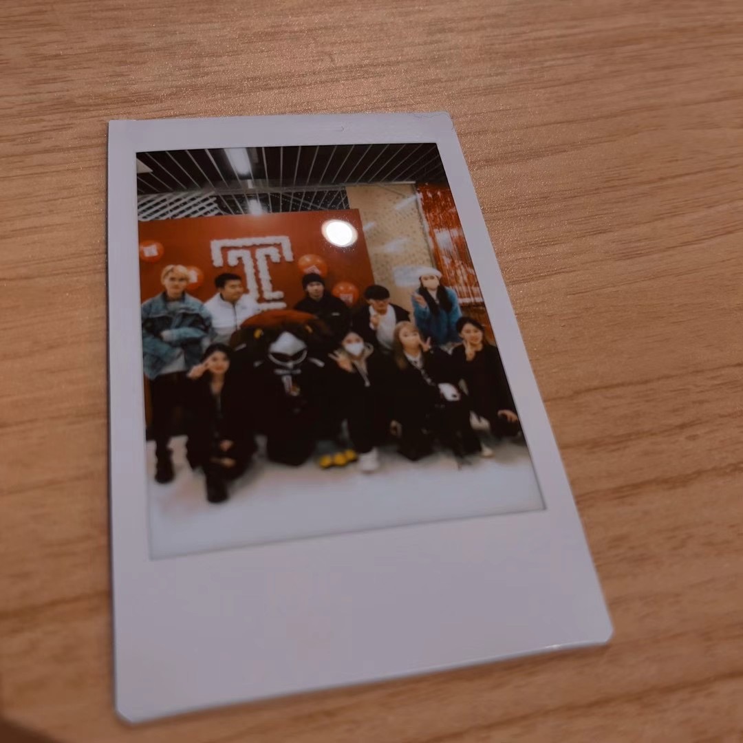 Polaroid group photo in front of the Temple logo